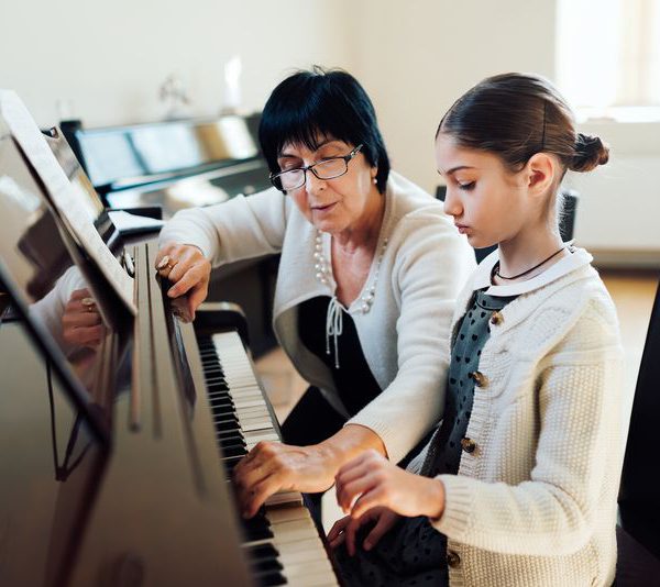 Girl learns Piano aside piano teacher