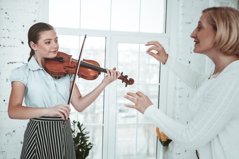 Geigenschülerin spielt Violine bei Geigenunterricht mit Geigenlehrerin
