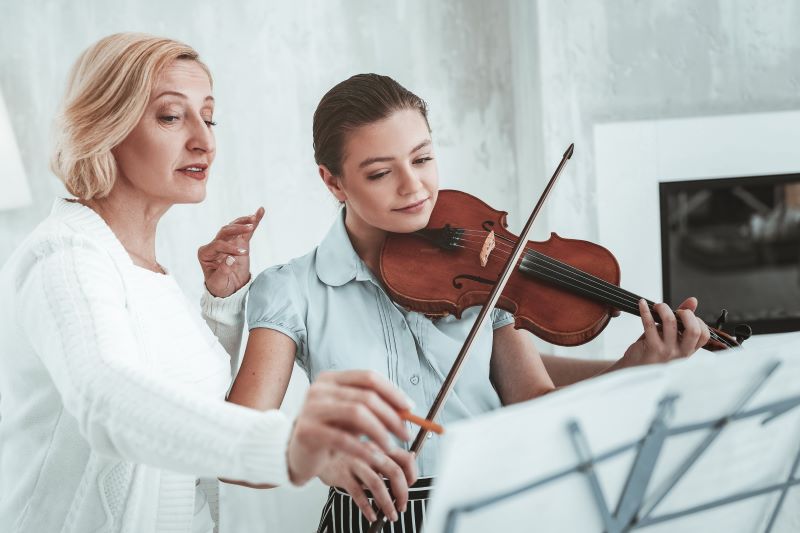 Ein Mädchen beim Geigenunterricht mit der Geigenlehrerin