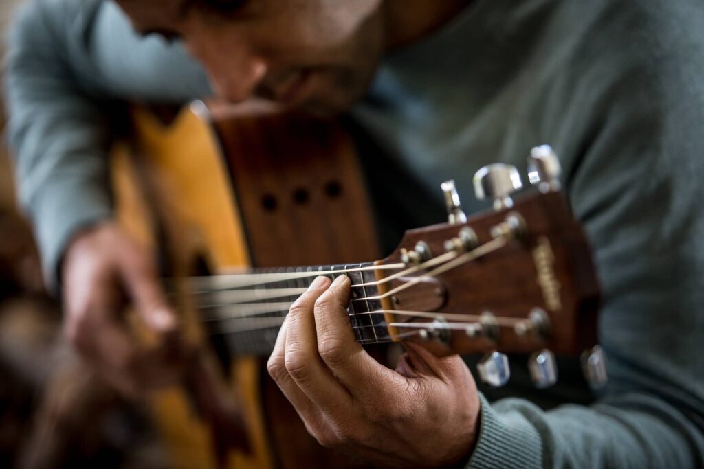 Gitarrenschüler spielt Akustikgitarre beim Gitarrenunterricht