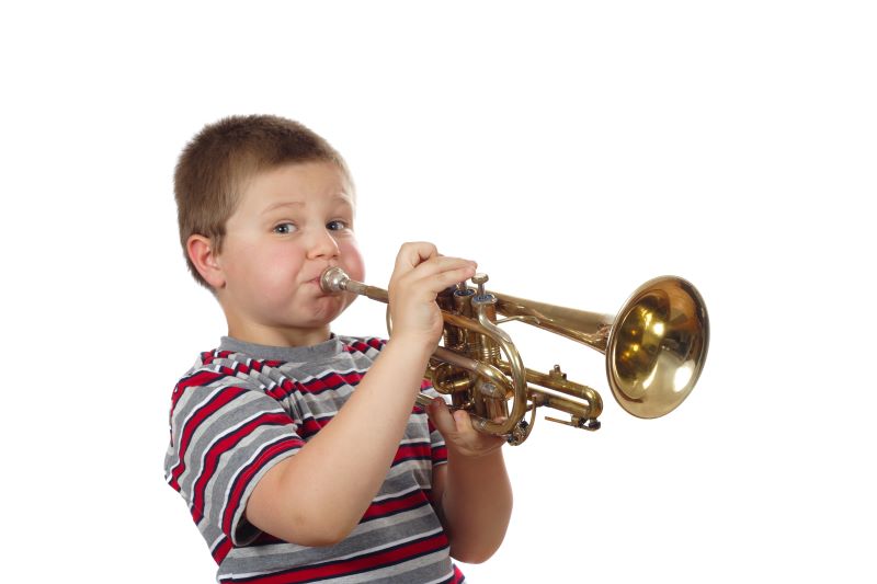 Ein Junge bläst in eine Trompete im Trompete-Musikunterricht